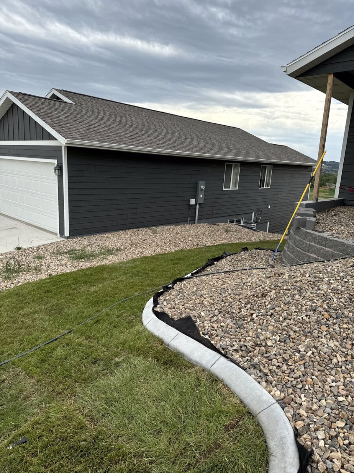 Continuous concrete curbing running along a fence line with rock fill