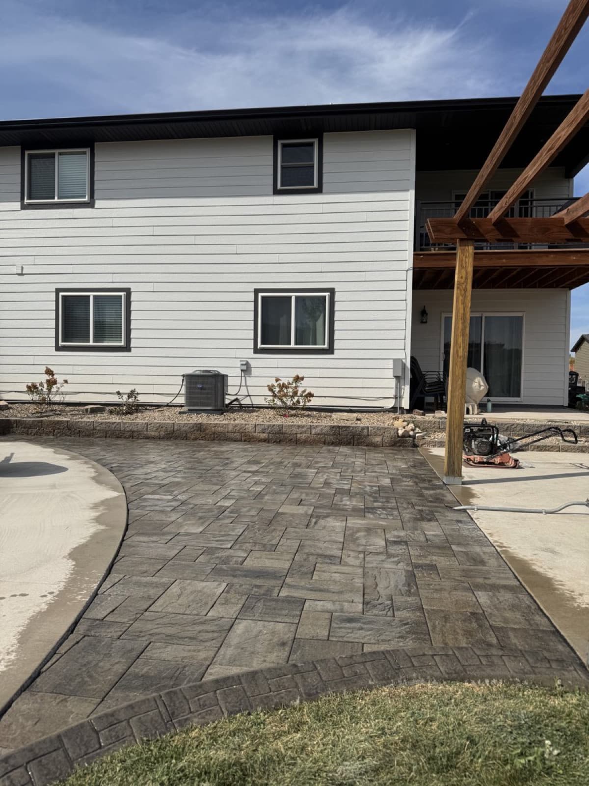 Completed paver patio with outdoor furniture and landscape lighting