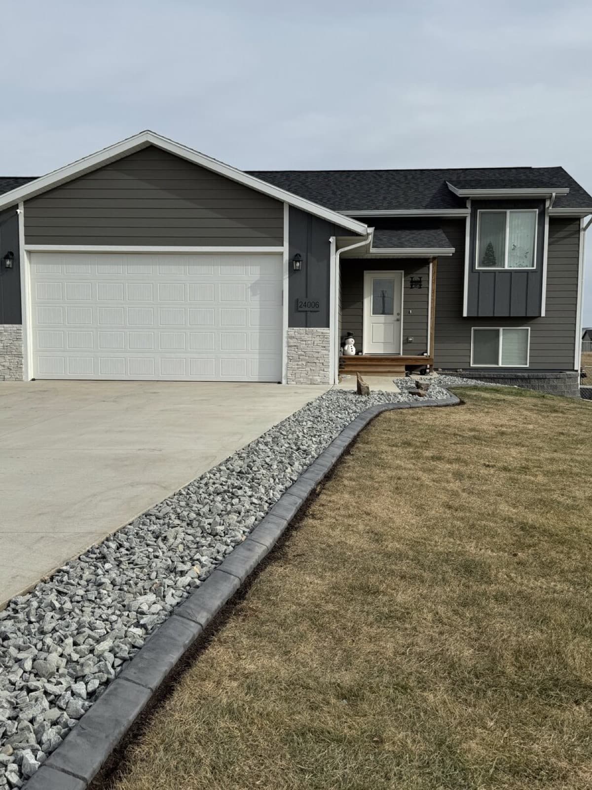 Rock border landscaping around a residential property with curbing accents