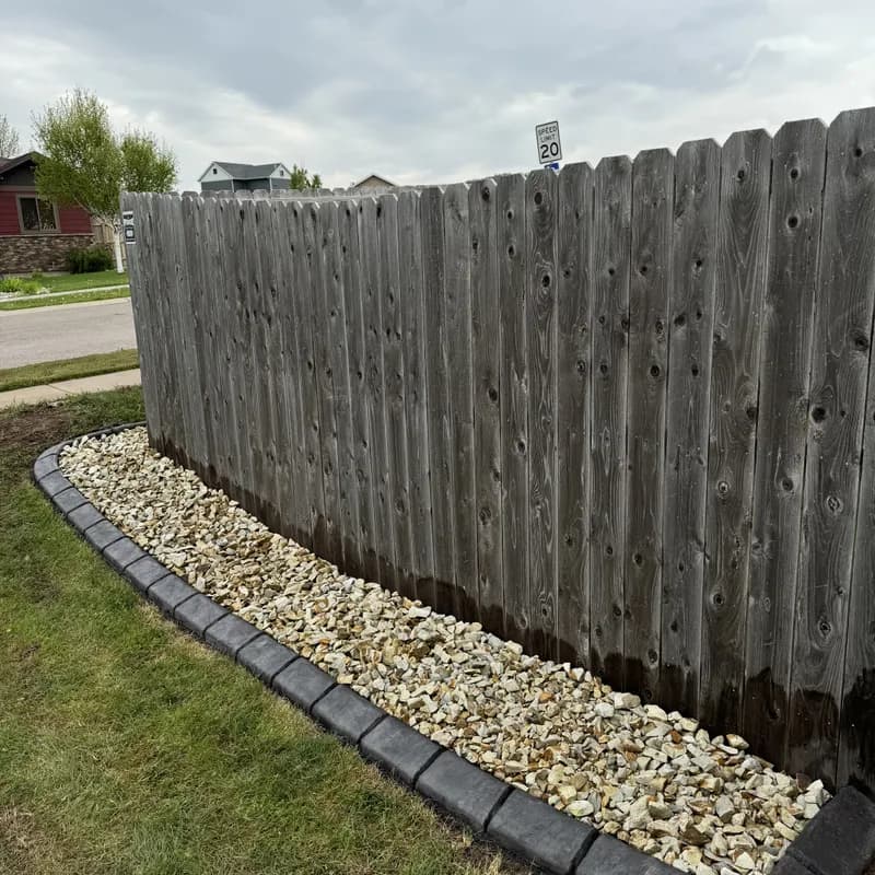 Concrete landscape curbing along fence line with decorative rock by ATK Landscaping in Rapid City