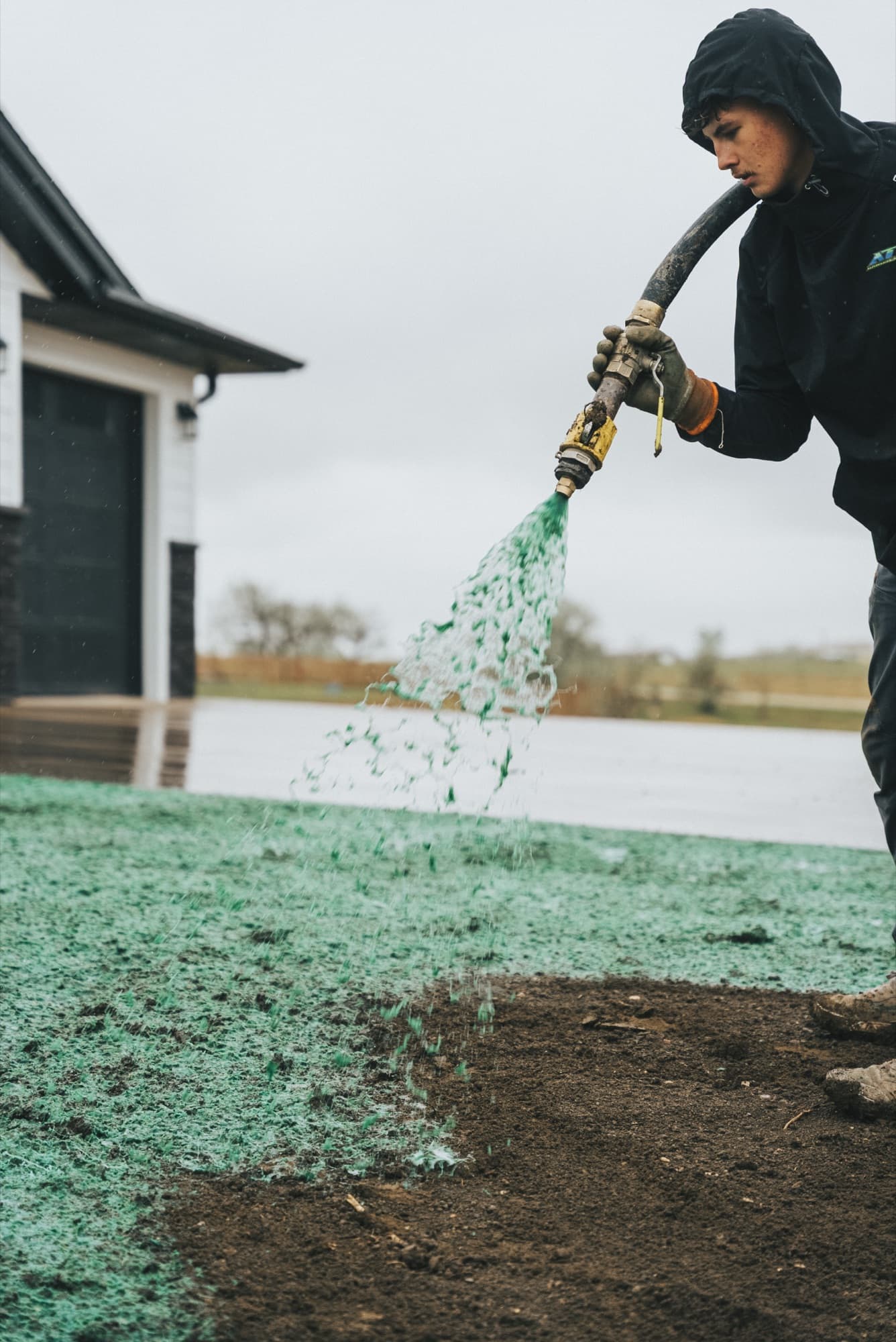 Close view of a worker spraying green mixture from a hose