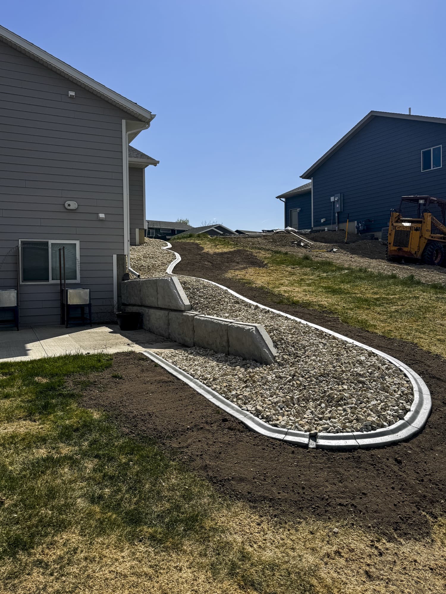 Curved curbing around a rock bed and stepped wall beside a house