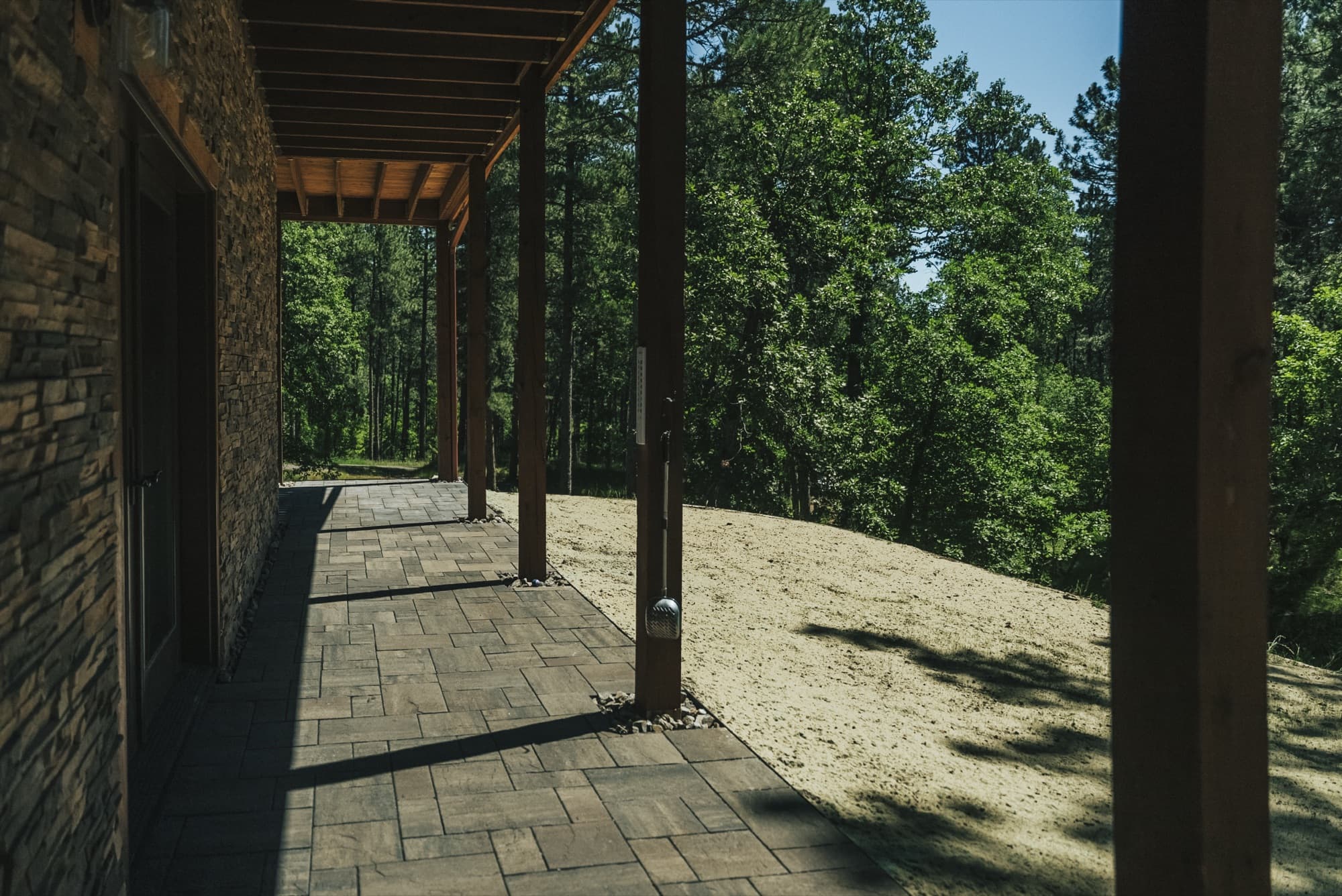 Paved walkway under a timber deck beside a stone-faced wall