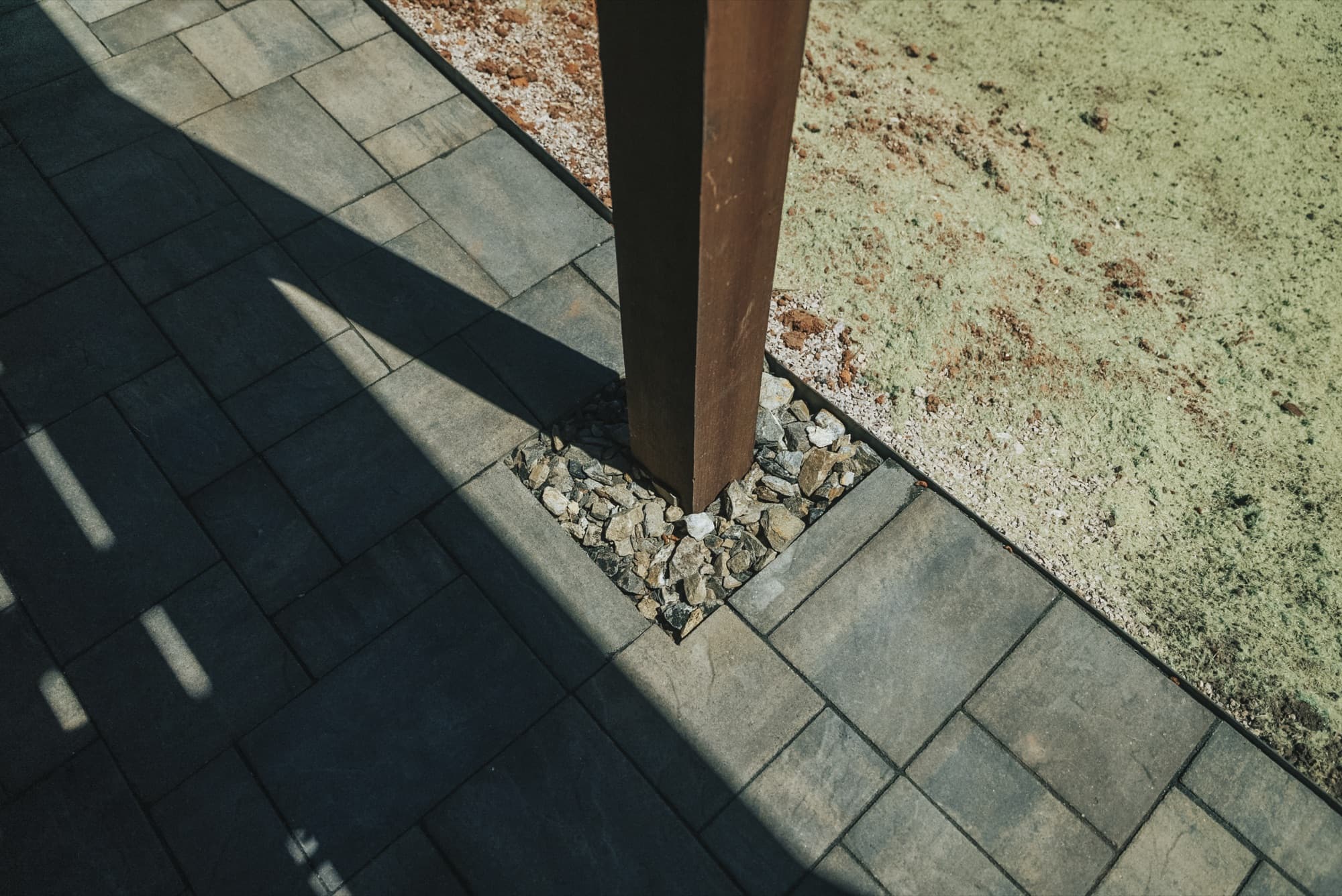 Pavers and loose rock fitted around a timber deck post