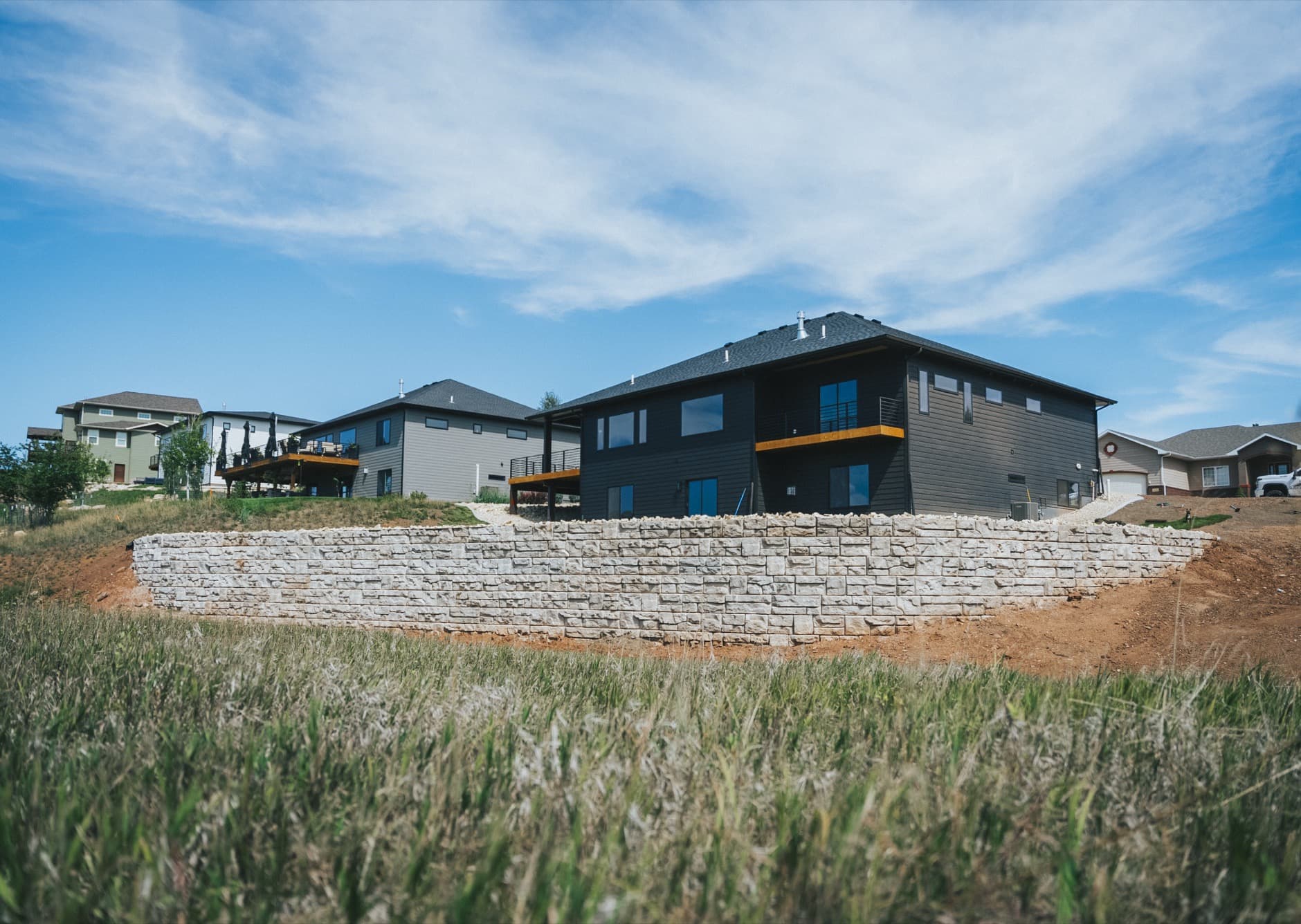 Long block retaining wall below a dark house on a slope