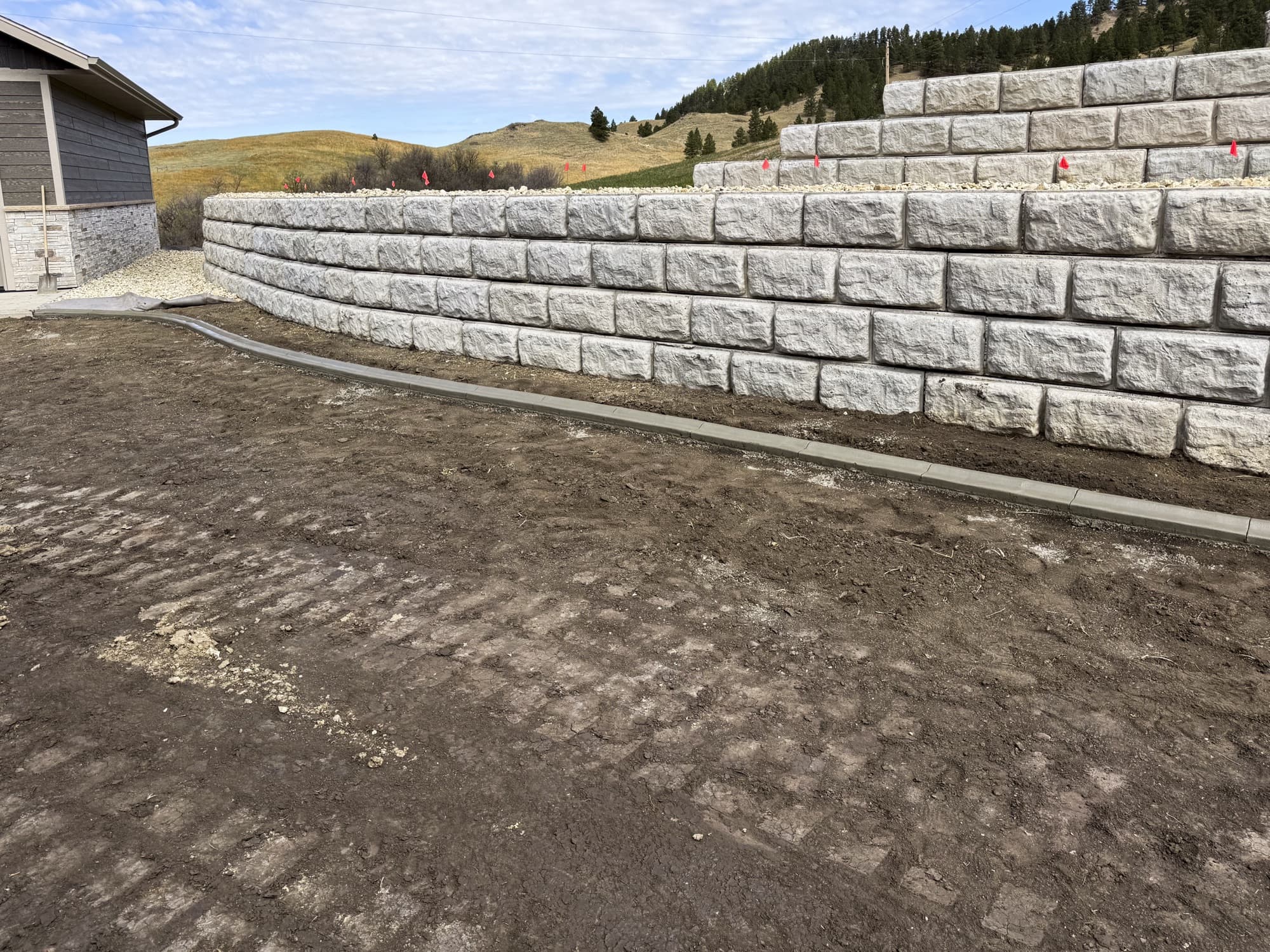 Two levels of pale block retaining walls beside a building
